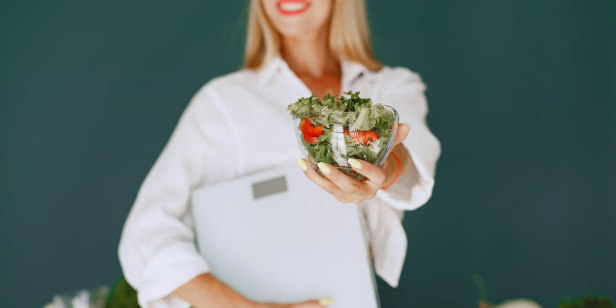 A woman with a vibrant smile offering a fresh salad bowl, promoting healthy eating.