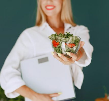 A woman with a vibrant smile offering a fresh salad bowl, promoting healthy eating.
